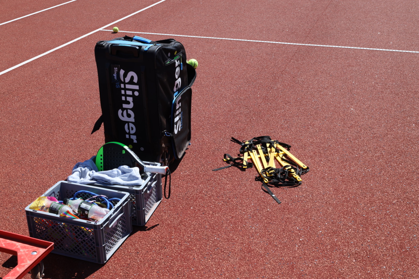 Ballwurfmaschine und Trainingsmaterial auf dem Tennisplatz